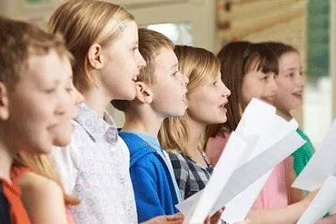 Kinderchor singt, Notenblätter haltend.